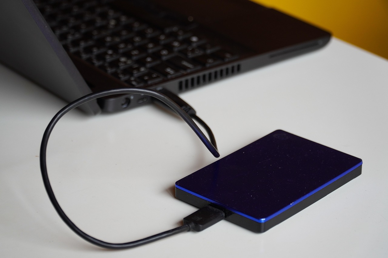Przenośny dysk zewnętrzny podłączony kablem USB do laptopa