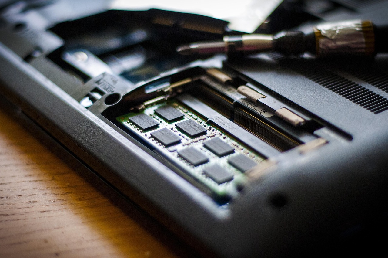 Moduł pamięci RAM montowany w slocie laptopa obok śrubokręta