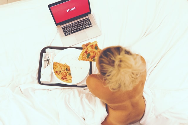 Kobieta leżąca na łóżku oglądająca Netflix